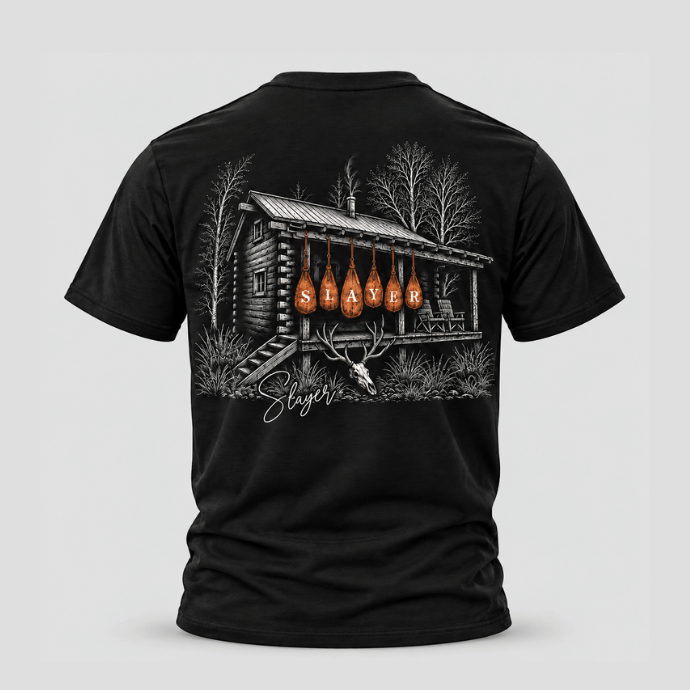 Black t-shirt with a graphic design of orange game bags hanging from the eves of an old hunting cabin on the back against a light gray background.
