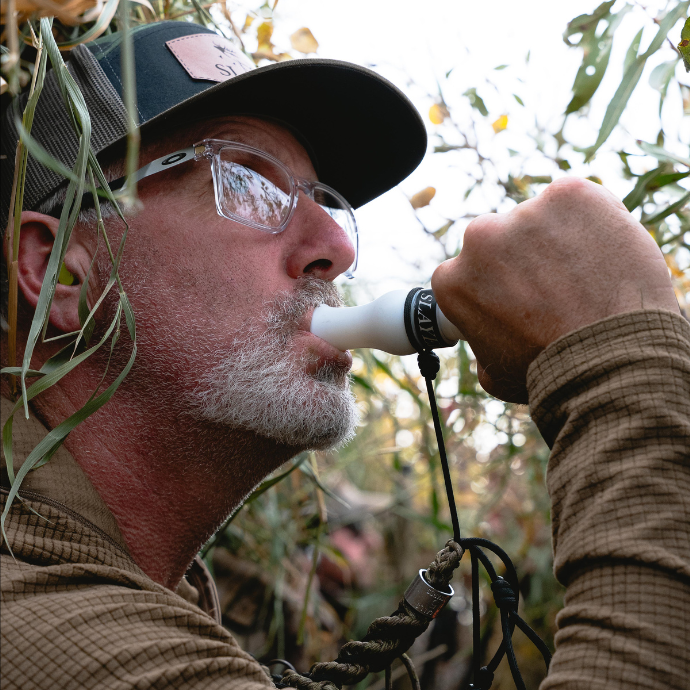 Waterfowl hunter blowing Slayer's Snowstorm snow goose call in a blind