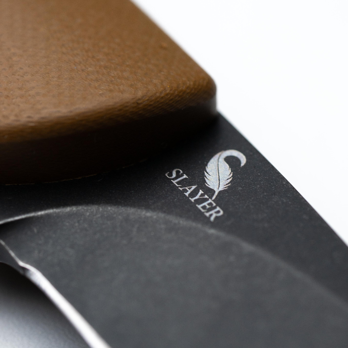 Close-up of a knife with 'SLAYER' branding with a brown handle.