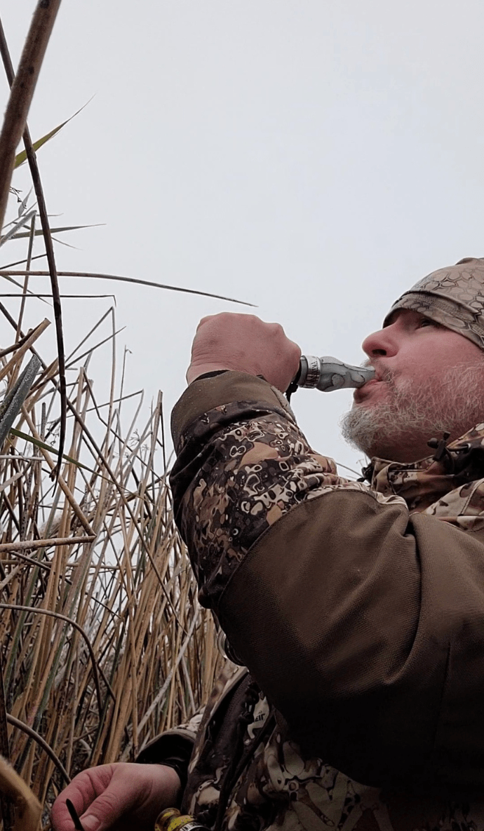 Hunter calling in geese using Slayer's Honker goose call in snow mesh