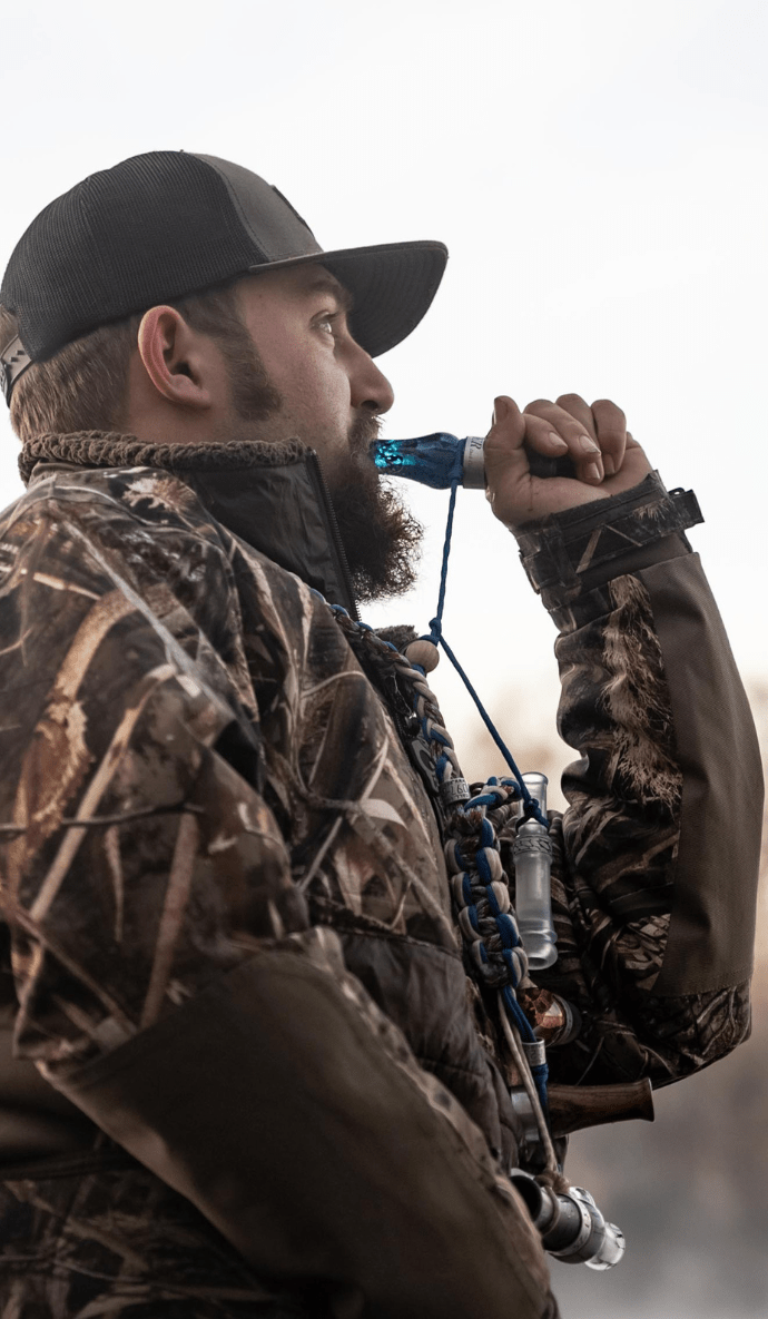 Hunter demonstrating the drake slayer double reed duck call in blue wing mesh