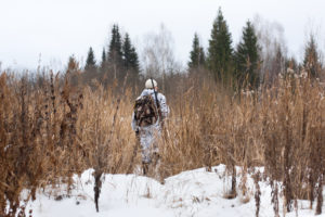 Duck hunter walking on a winter field