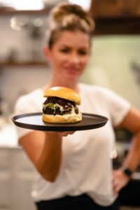 Bri Van Scotter holding Slayer duck burger on serving tray