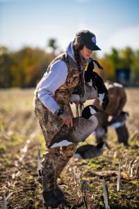 Woman hunter sets up silhouette decoys in field