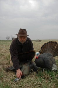 Hunter kneeling next to turkey and turkey decoy