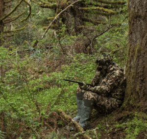 Turkey hunter safety: turkey hunter wearing full camo sits by tree