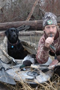 Hunting bluebills, hunter M.D. Johnson with dog in camo calling in the bluebills