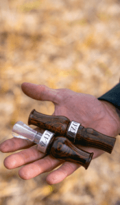 Duck hunter holding Slayer's matching duck goose combo: The Axe wood goose call featured next to the Suzie Slayer wood duck call